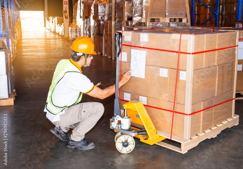 warehouse worker in uniform inspecting checklist detail of product pallet to transport.