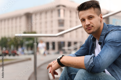 Portrait of handsome young man sitting on stairs outdoors. Space for text Free Download Portrait of handsome young man sitting on stairs outdoors. Space for text - GFXLoad