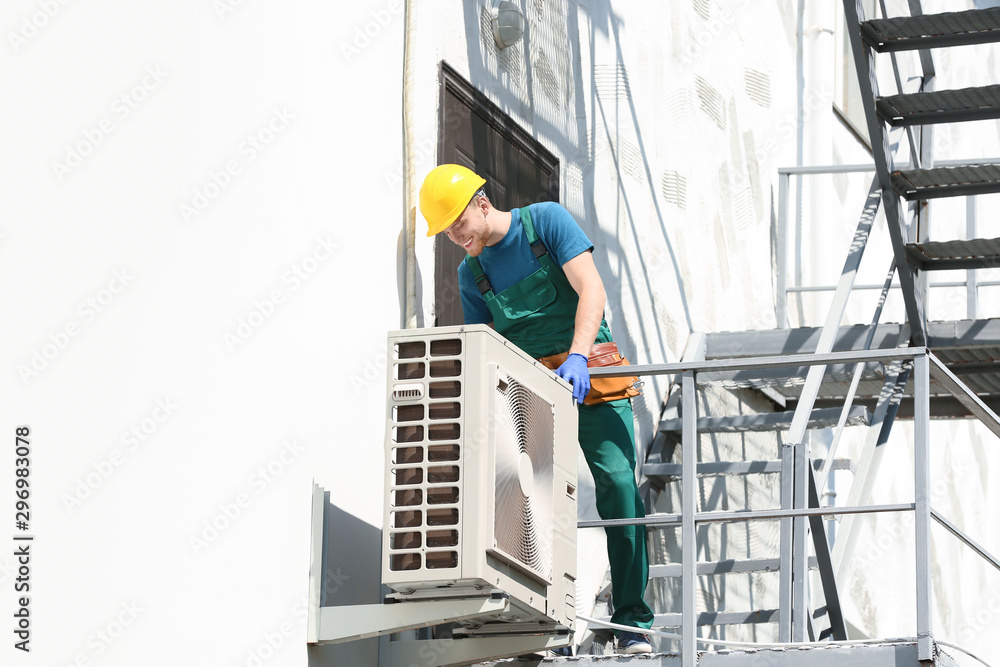 Professional technician repairing modern air conditioner outdoors Professional technician repairing modern air conditioner outdoors