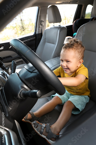 Little boy playing with steering wheel in car. Family trip