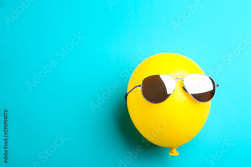 Balloon with sunglasses on blue background, top view. Space for text photo