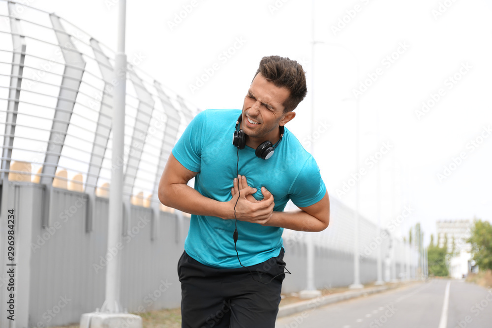 Fototapeta premium Young man having heart attack while running outdoors