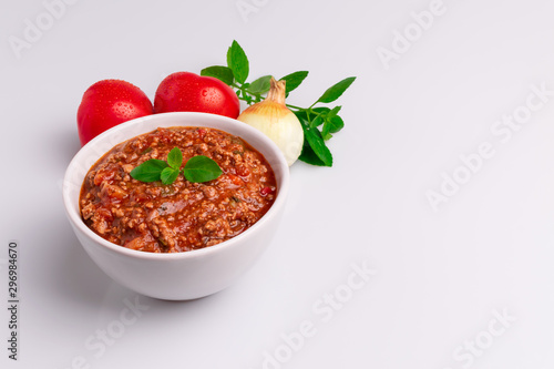 Bolognese (also know as Bolognesa or Bolonhesa) sauce in a white bowl isolated in white background, soft light, studio photo, copy space