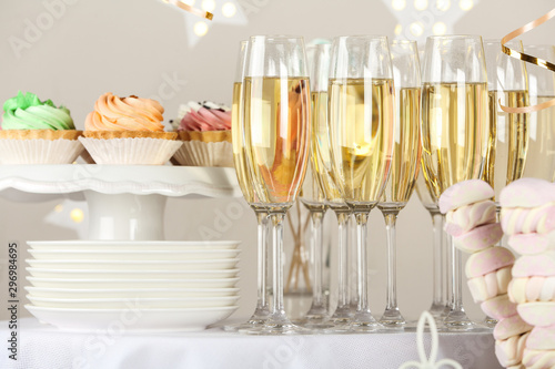 Candy bar with delicious treats and glasses of champagne for birthday party