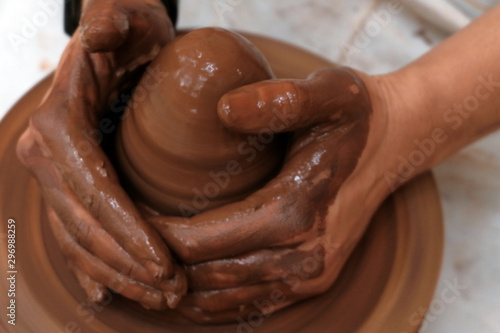 Blurred background on the theme of work with clay on a potter's wheel. Close-up of the movement of female or male hands. Soft focus. Craft. Handwork.