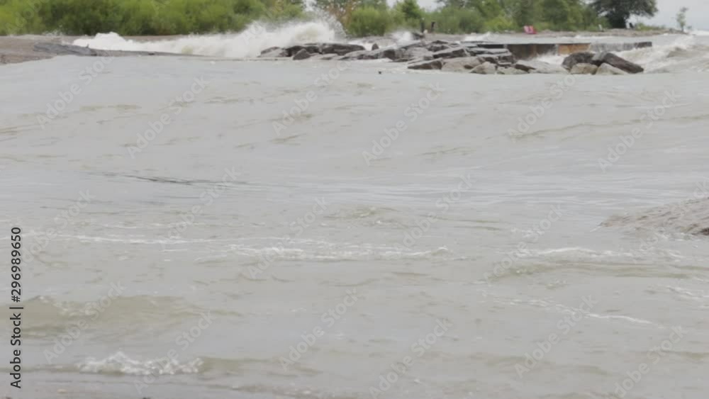Large waves crash onto the small rock islands. A beautiful wooded point can be seen in the background. Large waves crash onto the small rock islands. A beautiful wooded point can be seen in the background.
