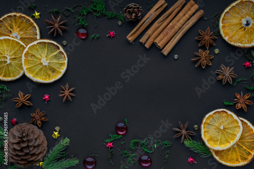 Merry Christmas and happy new year. composition on a black background of Christmas tree branches, cones, toys, cinnamon, dried oranges and anise. Greeting background, card or layout design. copy space