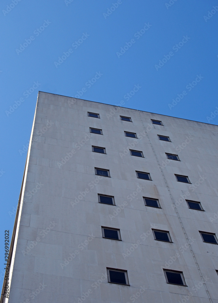 corner view of an old white 1960s concrete office block against a blue sky corner view of an old white 1960s concrete office block against a blue sky