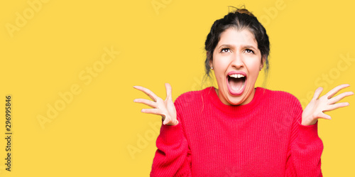 Young beautiful woman wearing red sweater and bun celebrating crazy and amazed for success with arms raised and open eyes screaming excited. Winner concept © Krakenimages.com