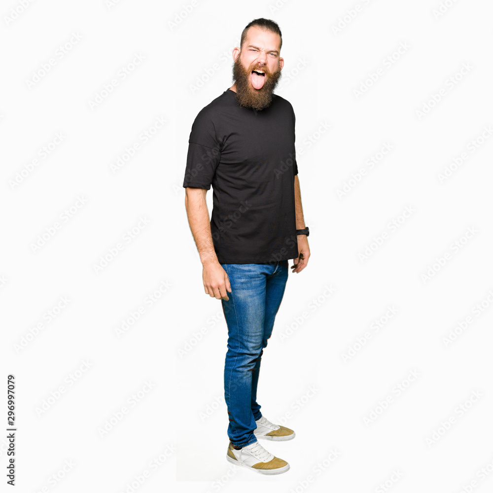 Young blond man wearing casual t-shirt sticking tongue out happy with funny expression. Emotion concept. Young blond man wearing casual t-shirt sticking tongue out happy with funny expression. Emotion concept.