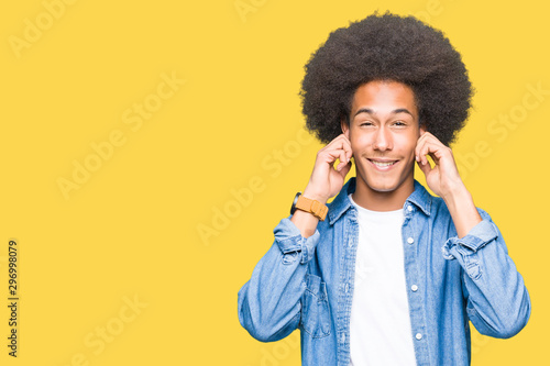 Young african american man with afro hair covering ears with fingers with annoyed expression for the noise of loud music. Deaf concept. © Krakenimages.com