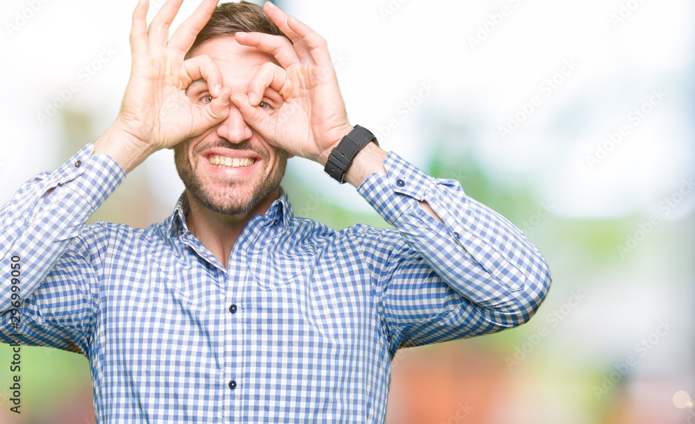 Handsome business man with blue eyes doing ok gesture like binoculars sticking tongue out, eyes looking through fingers. Crazy expression. Handsome business man with blue eyes doing ok gesture like binoculars sticking tongue out, eyes looking through fingers. Crazy expression.