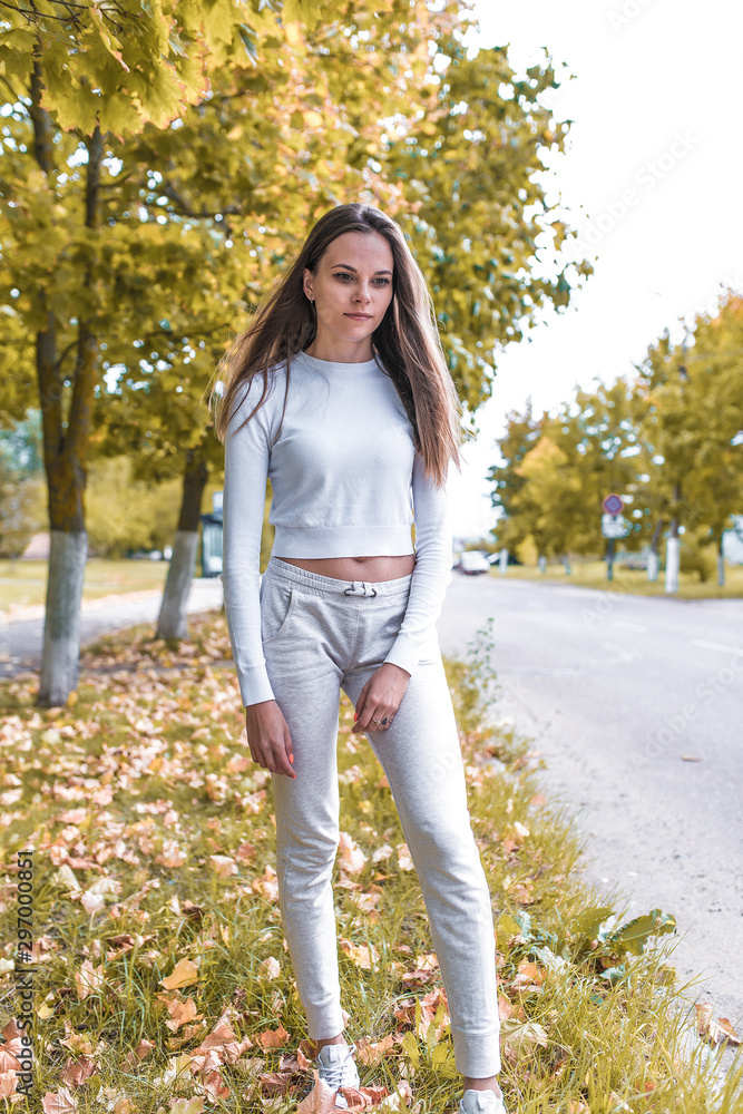 young and beautiful girl on the background of a tree and autumn leaves stands by the road, casual clothes. Emotions of positive and comfort. young and beautiful girl on the background of a tree and autumn leaves stands by the road, casual clothes. Emotions of positive and comfort.