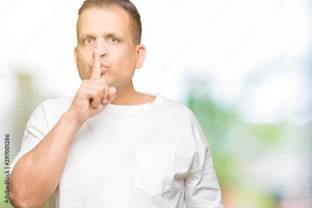Middle age arab man wearig white t-shirt over isolated background asking to be quiet with finger on lips. Silence and secret concept. Middle age arab man wearig white t-shirt over isolated background asking to be quiet with finger on lips. Silence and secret concept.