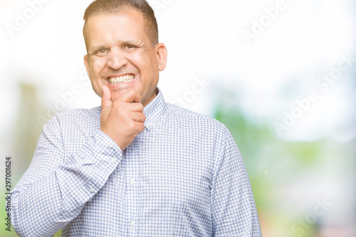 Middle age arab business man over isolated background looking confident at the camera with smile with crossed arms and hand raised on chin. Thinking positive.