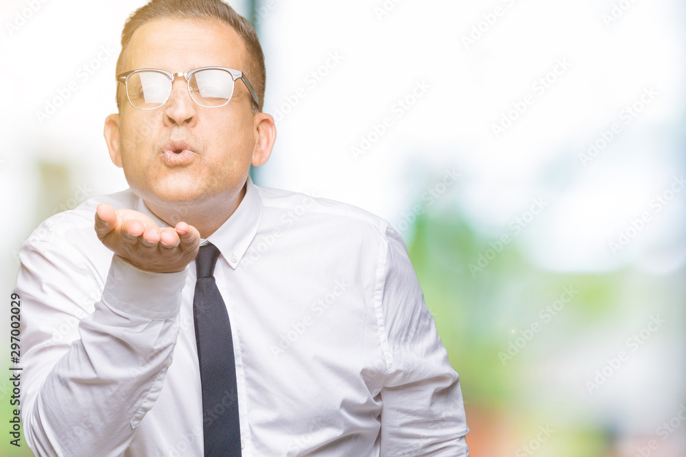 Middle age bussines arab man wearing glasses over isolated background looking at the camera blowing a kiss with hand on air being lovely and sexy. Love expression. Middle age bussines arab man wearing glasses over isolated background looking at the camera blowing a kiss with hand on air being lovely and sexy. Love expression.
