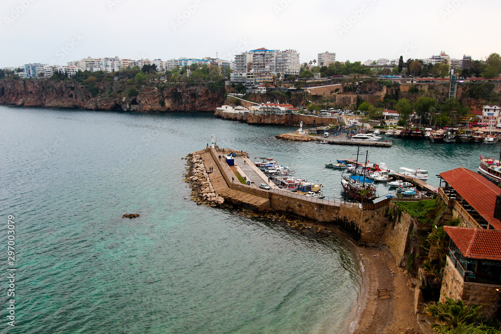 View of the tourist port. On the shore are hotels, an old fortress, yachts. Antalya, Turkey, April 6, 2019.