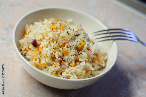 Hot steaming rice with vegetables under spices in a bowl with a fork