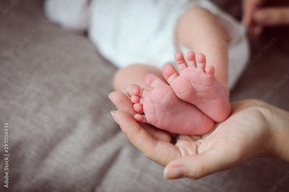 Mother's hand holding tiny newborn's feet closeup Mother's hand holding tiny newborn's feet closeup