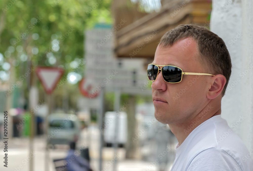 Portrait of a young man on a sunny day near the wall on a street background Portrait of a young man on a sunny day near the wall on a street background
