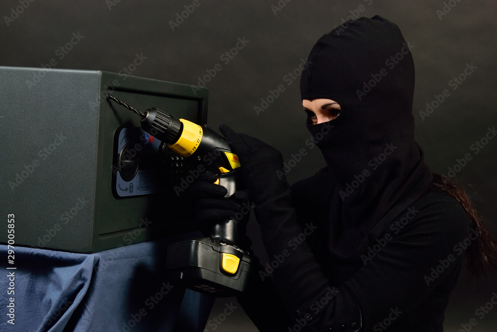 Girl thief breaks into the safe. She drills him Stock Photo | Adobe Stock