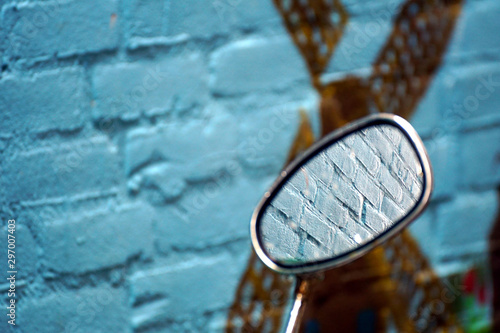 Bike mirror against a blue brickstone wall