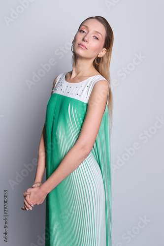 Beautiful model in light airy sleeveless sundress posing over gray background