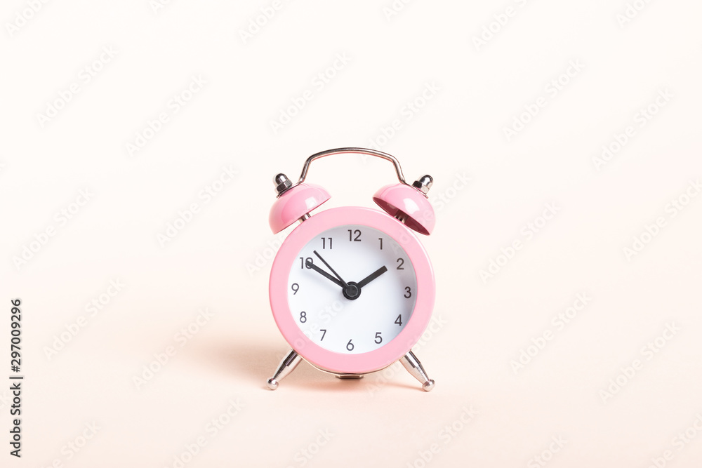 Little pink alarm clock on a pink background Little pink alarm clock on a pink background