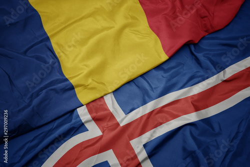 waving colorful flag of iceland and national flag of romania.