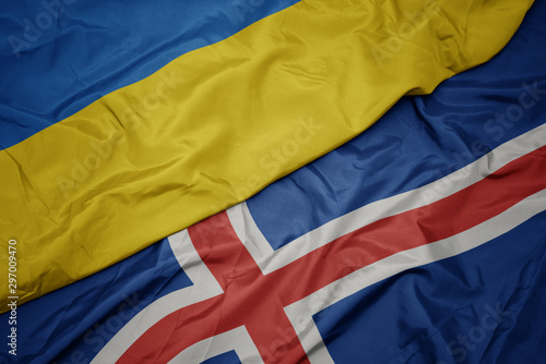 waving colorful flag of iceland and national flag of ukraine.