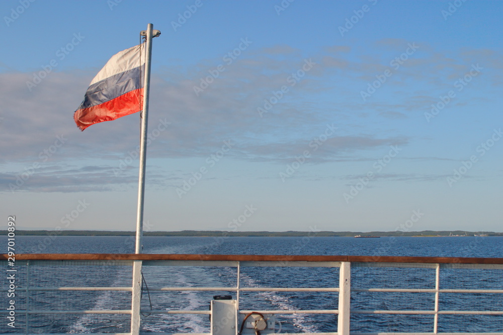 Fototapeta premium The image of the flag on the stern of the ship and the Wake