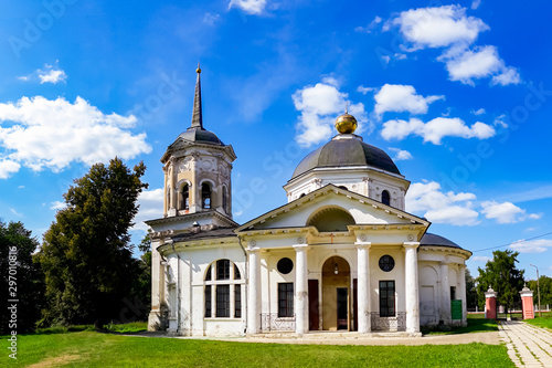 Beautiful christian church with golden domes among green trees. Church building on a sunny summer day.