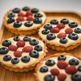 Homemade berry cakes with raspberries and blueberries on bamboo tray