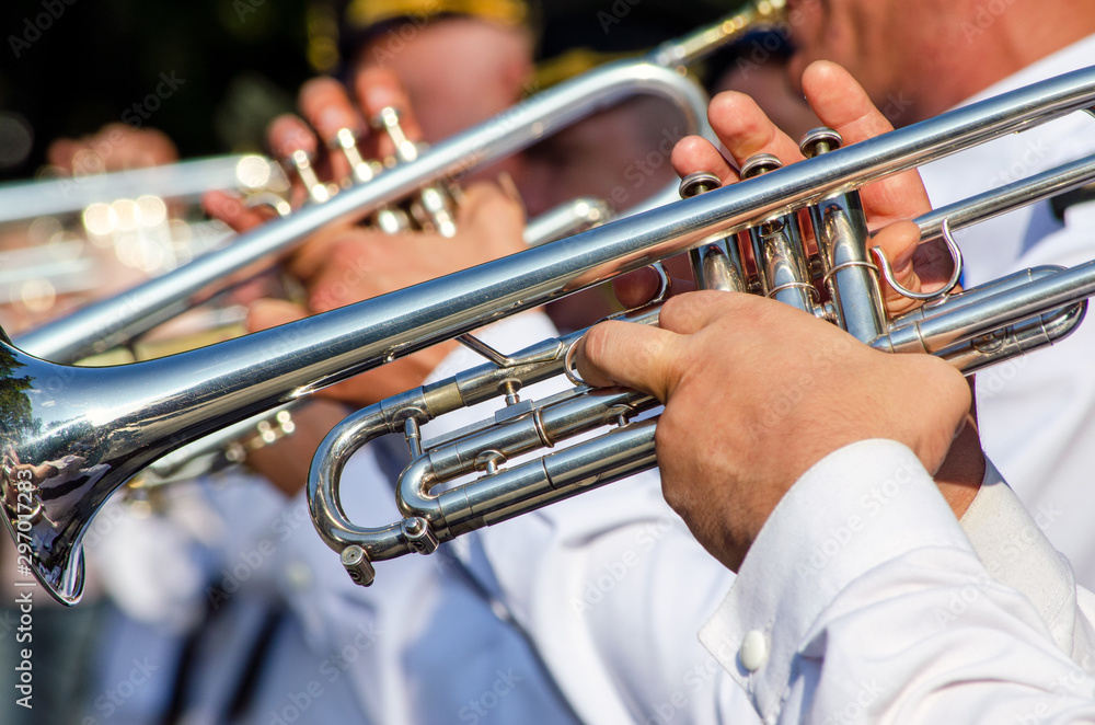 Obraz premium Hands of a man holding a trumpet musical instrument, a military band plays music