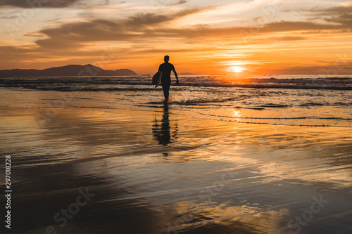 Silhouette of a surfer walking on the beach of the Atlantic Ocean, near San Sebastian and Bilbao, North of Spain