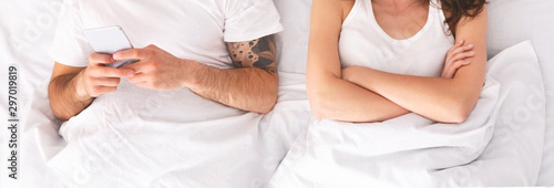 Man ignoring his offended wife in bed, playing video game