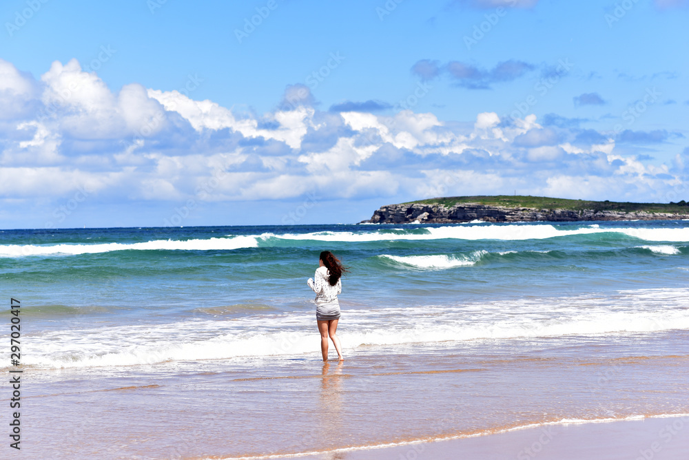 Young girl looking at the splashing wave on the beach of Playa de Somo İn Santander, Cantabria, Spain