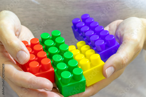 Hands of a woman holding colorful toy plastic bricks, blocks for building, playing games and entertainment concept