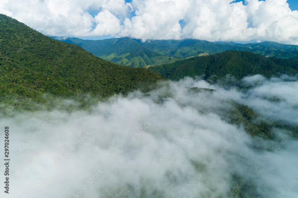 Aerial view drone shot of flowing fog waves on mountain tropical rainforest,Bird eye view image over the clouds Amazing nature background with clouds and mountain peaks