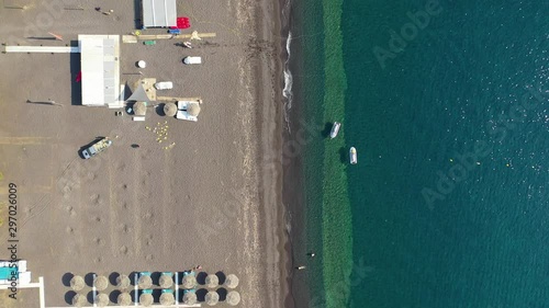 Aerial drone video of famous organised with umbrellas and sunbeds black sand beach and bay of Perissa village, Santorini island, Cyclades, Greece photo