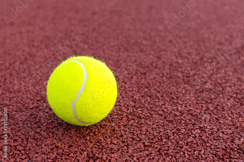 Yellow tennis ball on a brown court