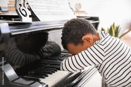 Fotografia Tired African-American boy sleeping at grand piano