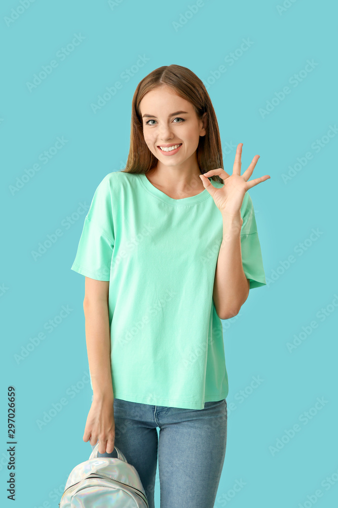 Beautiful female student showing OK on color background Beautiful female student showing OK on color background