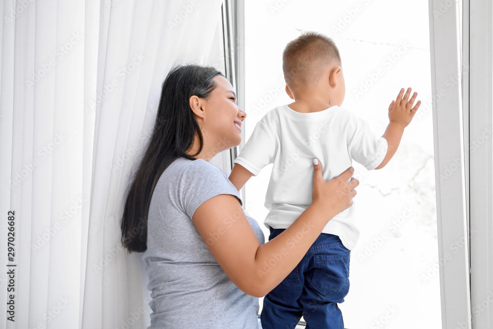 Asian mother and cute little baby near window at home Asian mother and cute little baby near window at home