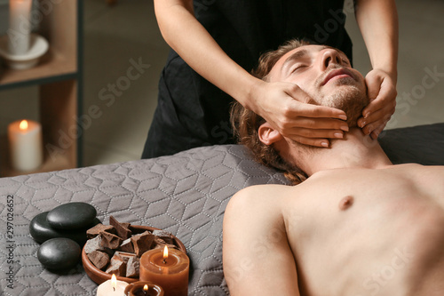 Young man receiving facial massage in spa salon