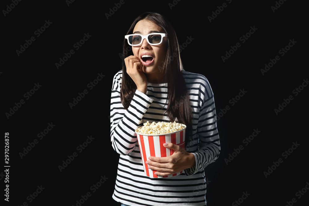 Fototapeta premium Afraid woman with popcorn on dark background