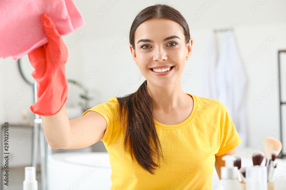 Beautiful young woman cleaning bathroom