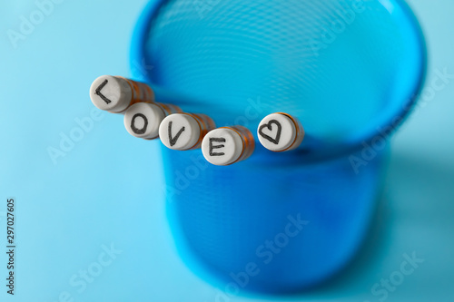 Word LOVE composed from pencils in holder on color background, closeup