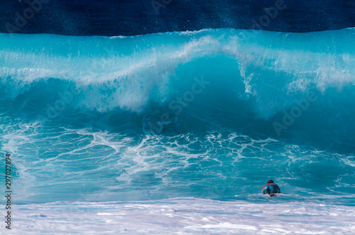 A Surfer diving under a big wave
