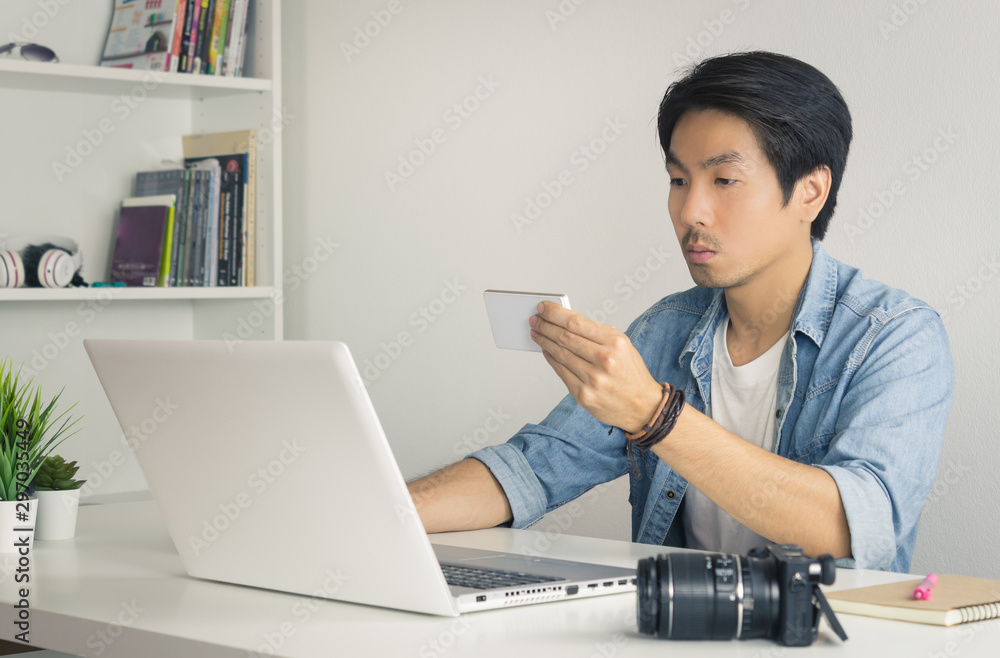 Asian Photographer or Freelancer Checking Photo File by Smartphone and Laptop in Home Office in Vintage Tone Asian Photographer or Freelancer Checking Photo File by Smartphone and Laptop in Home Office in Vintage Tone
